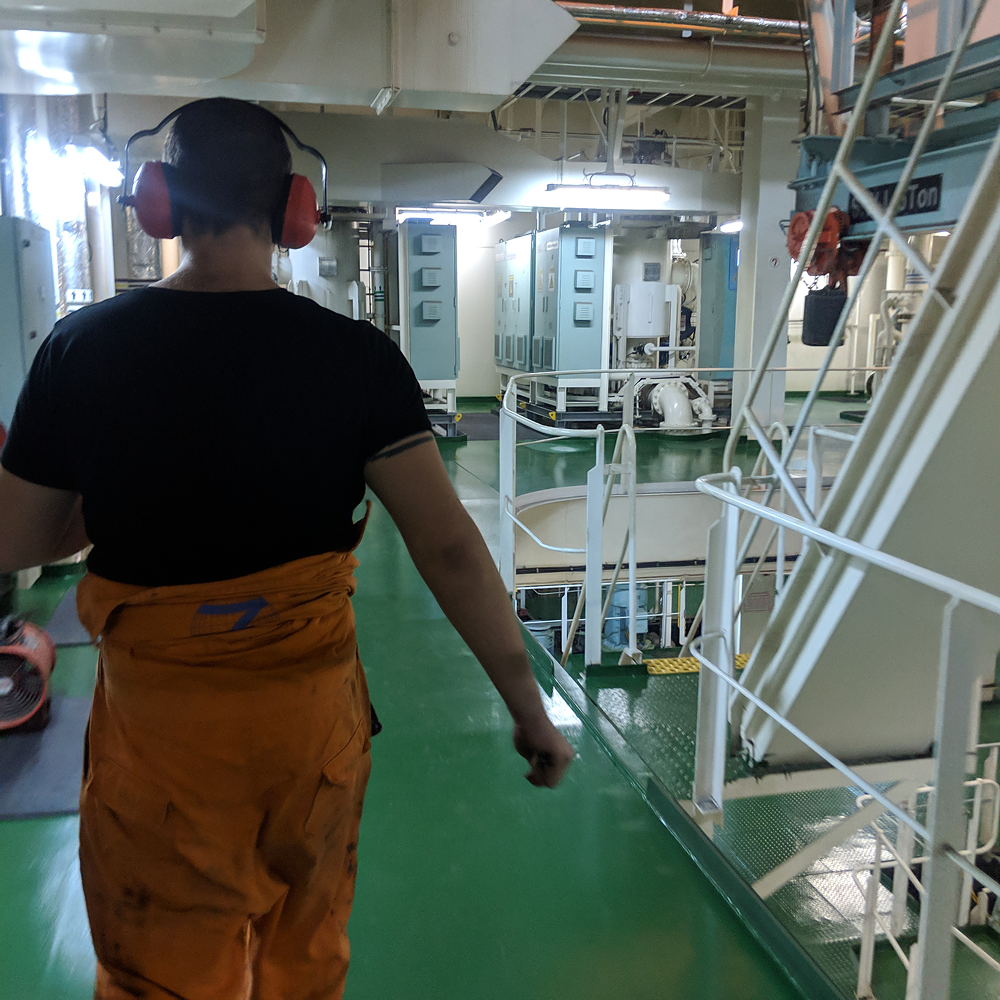 A crew member walking through the engine room